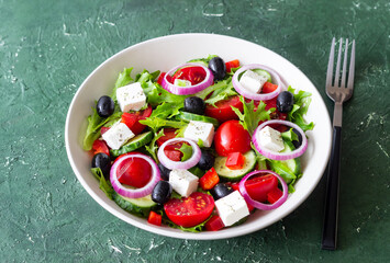Greek salad with feta cheese, tomatoes, onion, cucumbers, peppers and olives. Healthy eating. Vegetarian food.