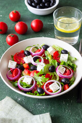 Greek salad with feta cheese, tomatoes, onion, cucumbers, peppers and olives. Healthy eating. Vegetarian food.