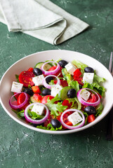Greek salad with feta cheese, tomatoes, onion, cucumbers, peppers and olives. Healthy eating. Vegetarian food.