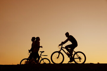 Fototapeta premium Scene of silhouette people in park or outdoor setting exercising enjoying nature. Family are walking. female Runner running or jogging. male Cyclists and young boy guy cycling bikes or bicycles
