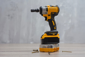 Cordless impact wrench on a wooden surface, accompanied by screws, drill bits, and a storage case. Electric tools for construction and DIY projects.