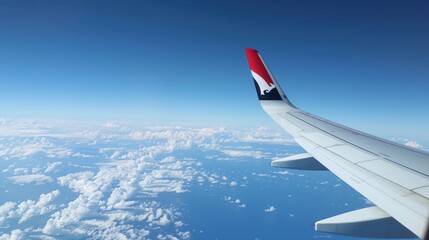 Airplane wing view from window with blue sky and clouds on a sunny day during air travel