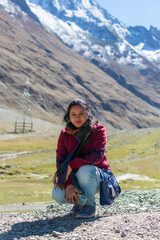 Portrait of an Indian female traveler enjoys the vibrant seasonal colors and panoramic landscape with Himalayan snow-capped mountains. Traveler, Tourist, adventure tourism, in Kashmir, India.