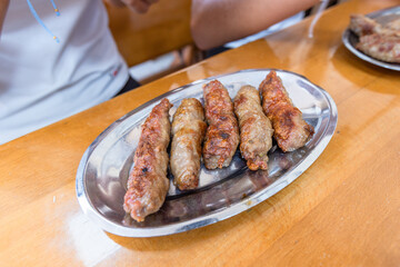 Traditional Balkan meal featuring grilled meat , flatbread, and chopped onions.