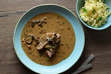 Top view of a traditional Czech dish — beef with mushrooms — served on a blue plate. A delicious autumn meal, rich in flavors, featuring tender beef pieces in a creamy mushroom sauce, food background