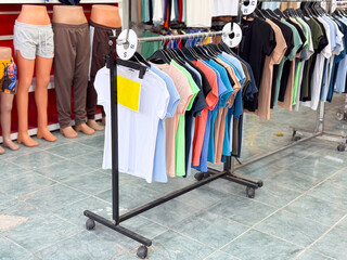 Colorful t-shirts displayed on racks at a street clothing store. Fashion apparel, retail shopping, casual textile display and seasonal wardrobe variety.