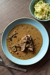 Top view of a traditional Czech dish — beef with mushrooms — served on a blue plate. A delicious autumn meal, rich in flavors, featuring tender beef pieces in a creamy mushroom sauce, food background