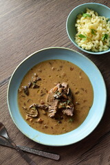 Top view of a traditional Czech dish — beef with mushrooms — served on a blue plate. A delicious autumn meal, rich in flavors, featuring tender beef pieces in a creamy mushroom sauce, food background