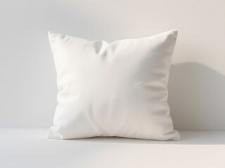 White decorative pillow with plain fabric surface placed in soft daylight on neutral wall background