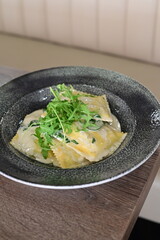 Spinach ravioli served with creamy sauce, delicious Italian pasta dish, gourmet presentation on a plate.