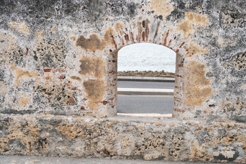 Old stone wall with arch window showing ocean and road in san juan, puerto rico