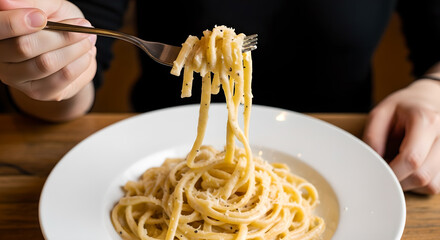 Person savoring creamy pasta dish with fork, enjoying a culinary moment, elegant spaghetti eating