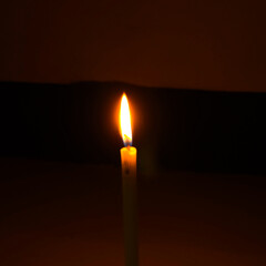 Fototapeta premium Glowing Candle Flame In Darkness