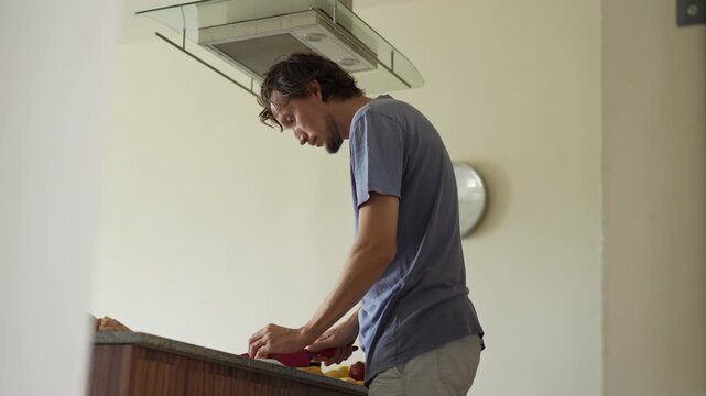 A young man is cooking food in the kitchen, focusing on preparing a delicious homemade meal. A relatable and warm moment of homemaking, creativity, and culinary enjoyment in a cozy setting.