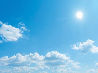 A beautiful clear blue sky with a bright shining sun and a few fluffy white clouds. A perfect summer day background.
