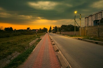 Obraz premium Scenic view of road amidst acacia trees and buildings against a golden sunset at Syokimau Suburb in Machakos County, Kenya 