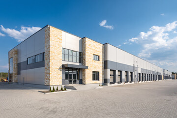 Modern warehouse building with loading docks and stone accents under a bright blue sky