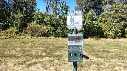 A dog waste bag station in the park, with information and images for dog owners, hygiene guidelines for pet owners in public places, and equipment for collecting dog excrement on walks