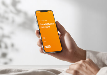 Woman hand holding smartphone on clean bright interior background