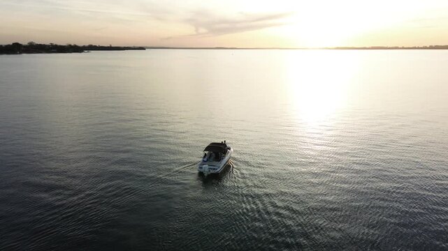 Imagens de uma lancha no rio ao por do sol feitas por drone