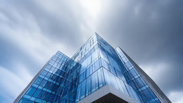 A modern glass office building with blue-tinted, reflective windows and angular architecture.