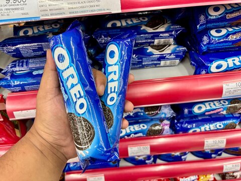 Hand holding two packages of Oreo cookies in supermarket