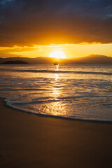 Fototapeta premium Golden sunset over the ocean with fishing boat and mountains
