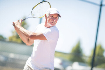 Active senior man playing tennis on an outdoor court. Concept of healthy aging, active lifestyle, and physical fitness in older age.