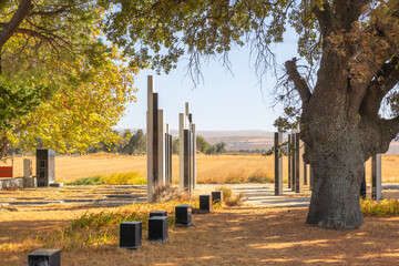 Kumkale Martyrs Cemetery monument with memorial columns framed by large tree and golden field in &Ccedil;anakkale, Turkey