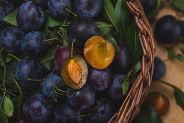 a plum cut in half lies on top of other whole plums