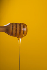 A jar of honey and a spoon, honey is pouring