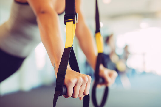 Close-up of hands gripping TRX suspension straps during a workout. Strength training and functional fitness concept.