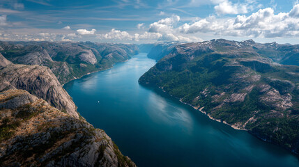 Obraz premium Aerial view of a blue river flowing through a mountainous landscape under a cloudy sky