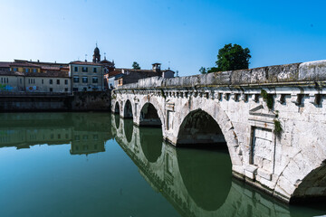 Fototapeta premium Ancient bridge over calm water, reflecting architecture and sky. A timeless landmark merges history with serene landscape.