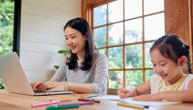Happy Asian mother with gentle smile works on laptop at rustic table while her cute daughter draws beside her. beautiful scene of family, home, and remote work - Powered by Adobe
