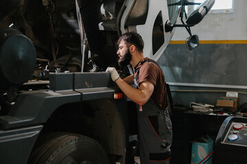Auto mechanic skillfully repairing large truck engine