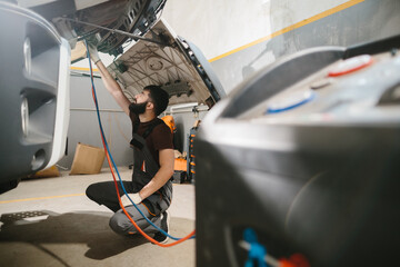 Auto mechanic repairing truck air conditioning system in garage