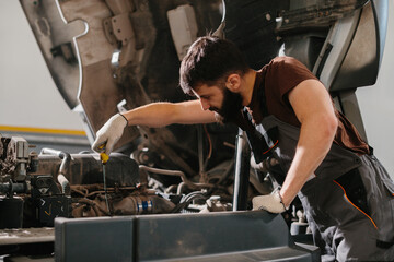 Mechanic checking oil level of truck engine in garage