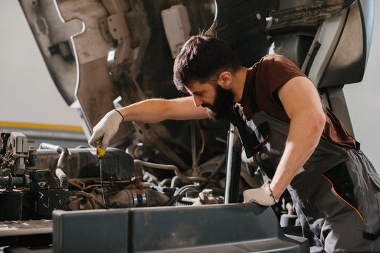 Mechanic checking oil level of truck engine in garage - Powered by Adobe