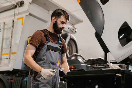 Mechanic repairing truck engine in garage workshop