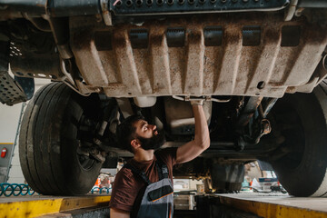 Skilled mechanic inspecting underneath a large truck