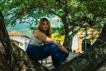 Young Latina woman sitting on tree in Colombian colonial town