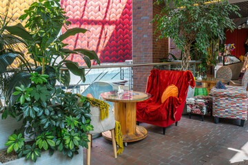 Cozy interior with plants, unique table, and comfortable seating creates a welcoming and inviting space for relaxation and socializing.