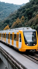 Obraz premium Modern yellow and white train traveling through mountainous landscape on an overpass during a clear day in a scenic area