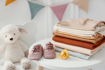 Stack of clean baby clothes and accessories on white table indoors, closeup