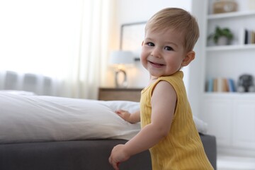 Cute little baby near bed at home