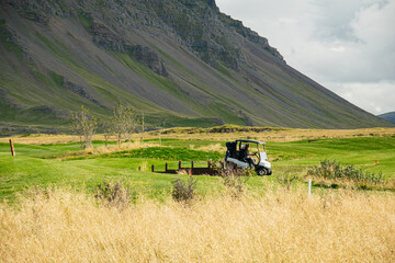 Naklejka premium Golf course in stunning Icelandic landscape with rocky mountains and rolling green fields