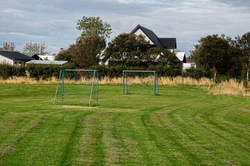 Scenic Icelandic soccer field with goalposts surrounded by serene suburban houses