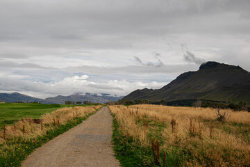 Scenic path through Icelandic landscape with mountains under a cloudy sky
