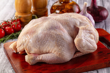 Raw whole chicken over board